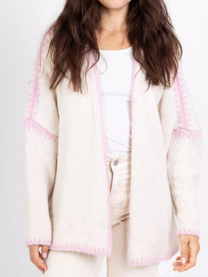 Cream oversized cardigan with contrast pink trim and textured sleeves.