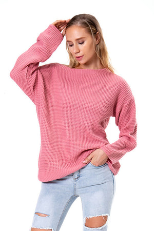 Hot pink waffle knit sweater with boat neck and slouchy fit, styled with ripped jeans.