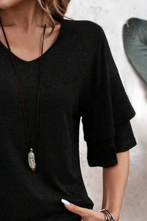 Black jersey tee with tiered short sleeves and V-neck, styled with a feather pendant necklace.