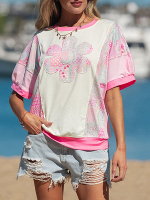 Maternity t-shirt with floral patchwork, crew neck, short sleeves, and pink trim.