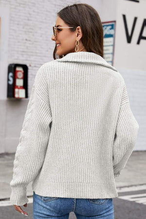 Gray cable knit zip-up sweater with a collar and textured sleeves.