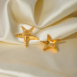 Gold starfish stud earrings with textured detail on a satin background.