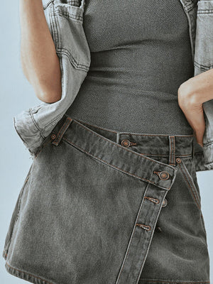 Gray denim skort with asymmetrical button-front detail and visible stitching.