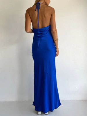 Blue satin halter maxi dress with asymmetric hem and open back.