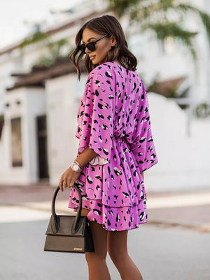 Tropical tiered mini dress in fuchsia pink with leopard print, V-neck, flutter sleeves, and ruffled hem.