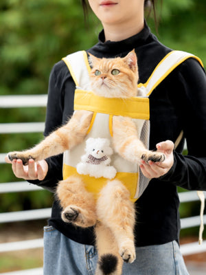 Front-pack pet carrier in yellow and beige with a teddy bear detail, worn by a person.