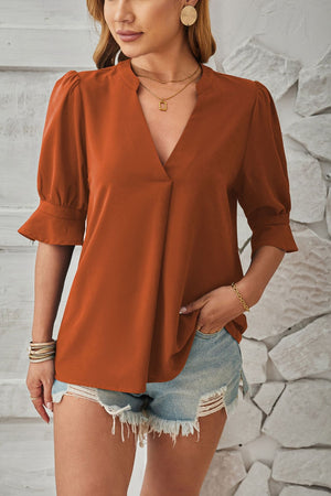 Brown puffed sleeve flared cuff blouse with V-neck and gathered shoulders.