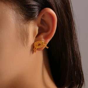 Golden bow stud earrings with a textured knot design.
