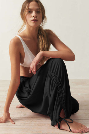 Gathered ankle-tie balloon trousers in black, breathable fabric.