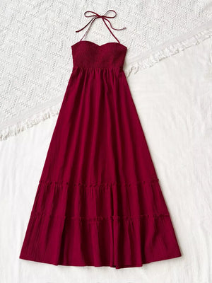 Burgundy halter neck maxi dress with smocked bodice and tiered skirt.