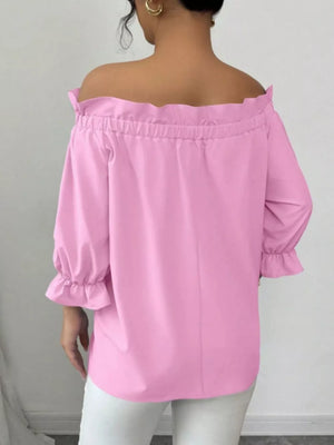 Pink off-the-shoulder blouse with ruffled neckline and cuffs.