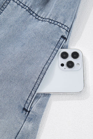 Gathered waist denim mini dress in medium wash with a phone in the pocket.