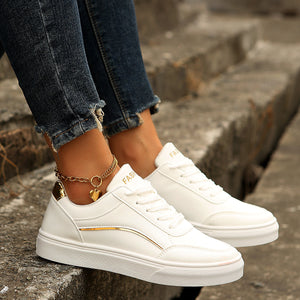 White lace-up casual sneakers with gold accents and a heart charm anklet.