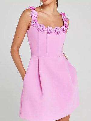 Pink mini dress with floral embellishments on the neckline and straps, featuring pockets.