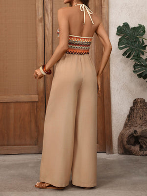 Beige wide-leg halter jumpsuit with colorful geometric patterned bodice and tie back.