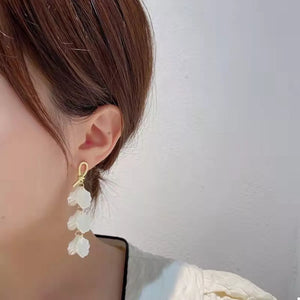 Elegant beige shell drop earrings with gold knot detail.