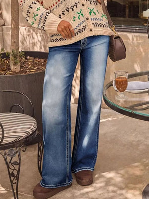 Light blue denim jeans with a high waist and flared leg, styled with a patterned cardigan.