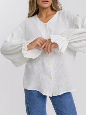 White textured puff sleeve blouse with ruffled cuffs and V-neck.