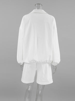White two-piece set with collared long sleeve top and drawstring shorts, featuring snap details.