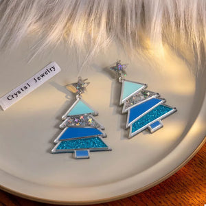 Blue acrylic Christmas tree dangle earrings with glitter and star accents.