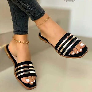 Black open-toe flat sandals with metallic stripe detail.