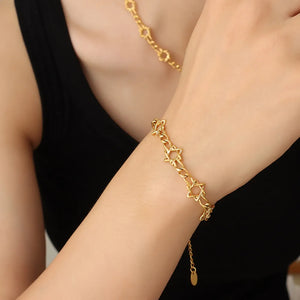 Gold chain bracelet with star links and a delicate pendant detail.