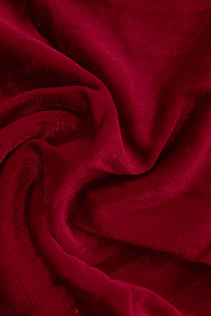 Plush velvet wide-leg trousers in burgundy, showing fabric texture and drape.