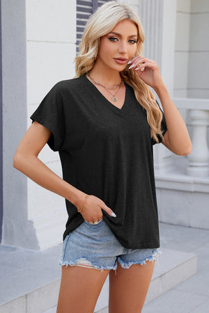Black dolman sleeve slouchy v-neck top with cuffed sleeves, styled with denim shorts.