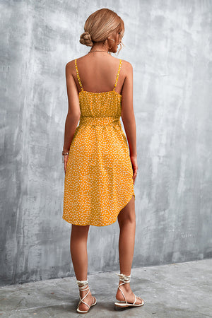 Mustard daisy print tie-waist slip dress with a ruffled hem and spaghetti straps.
