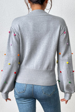 Light gray blouson sweater with colorful pom-pom embellishments on sleeves and shoulders.