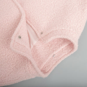 Blush pink textured bouclé bomber jacket with rounded neck and snap closure detail.