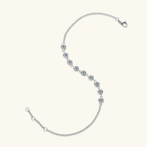 Silver moissanite tennis bracelet with bezel-set stones and a delicate chain.