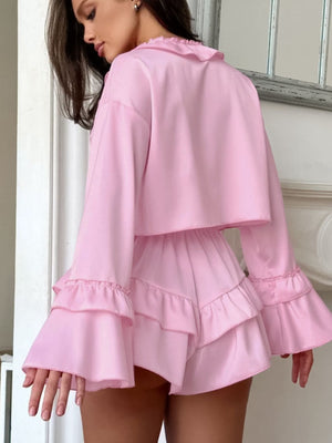 Pink pajama set with ruffled V-neck, bell sleeves, and tiered ruffled shorts.