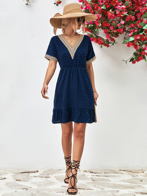 Dark blue Swiss dot dress with crochet trim V-neck, elastic waist, and ruffled hem.