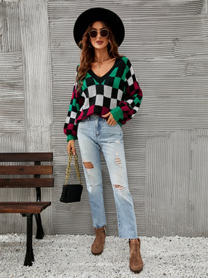 Geometric V-neck knit sweater with puff sleeves in black, green, white, and pink checkerboard pattern.