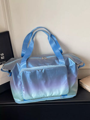 Iridescent gradient blue duffel bag with dual handles and front pocket.