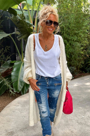 White maxi knit cardigan with open front and balloon sleeves, worn over a white tank top and distressed jeans.