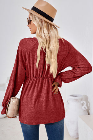 Burgundy long sleeve blouse with elastic cinched waist and billowy sleeves.