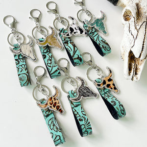 Embossed leather bull keychains with crystal accents in various animal prints and turquoise.