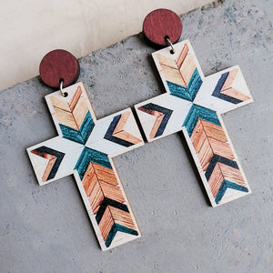 Geometric cross statement earrings with wood post and tribal pattern in beige, teal, and orange.