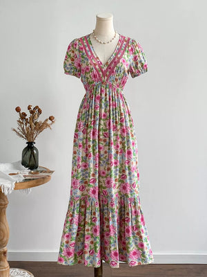 Maxi dress with V-neck, short puff sleeves, floral print, and decorative trim.