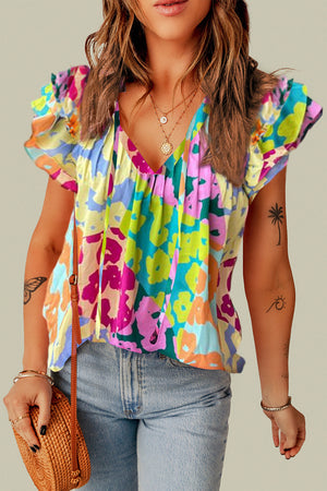 Floral patchwork blouse with ruffle sleeves and tie neck in vibrant colors.