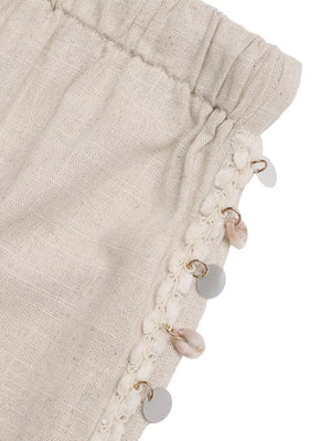 Relaxed drawstring wide-leg trousers in natural linen with shell and disc embellishments.