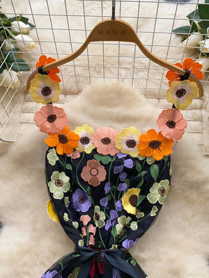 Black mini dress with colorful floral embroidery and applique flowers around the neckline.