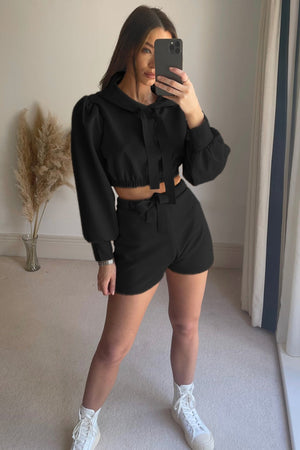 Black cropped hoodie with tie detail and puff sleeves, paired with matching shorts.
