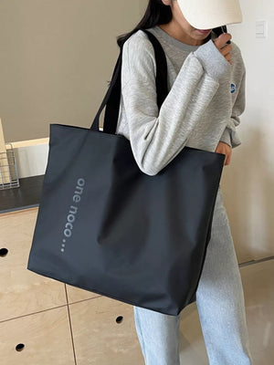 Minimalist black large shoulder bag with text detail, casual tote for women.