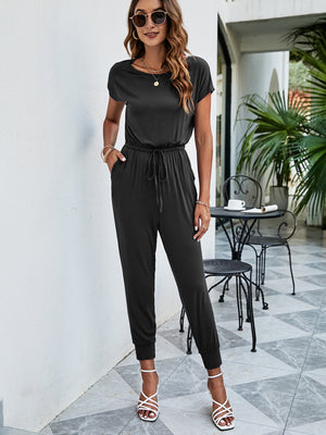 Black jersey jumpsuit with short sleeves, drawstring waist, and cuffed ankles.