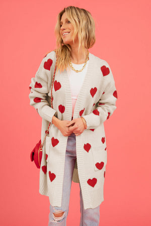 Cream longline knit cardigan with red heart motif, pockets, and open front.