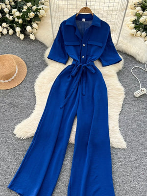 Blue belted wide-leg maternity jumpsuit with pockets and buttoned chest pockets.
