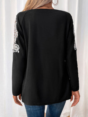 Black ribbed knit zip-front top with white lace trim on sleeves.